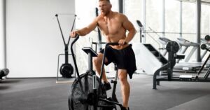 En mand træner på en airbike i bar overkrop