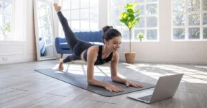 Kvinde dyrker yoga på en yogamåtte i hjemmet