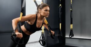 Ung kvinde træner med TRX udstyr